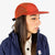 Topo Designs Global mesh back Hat in Clay orange on model.